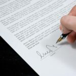 Close-up of a hand signing a formal document with a fountain pen, indicating agreement.